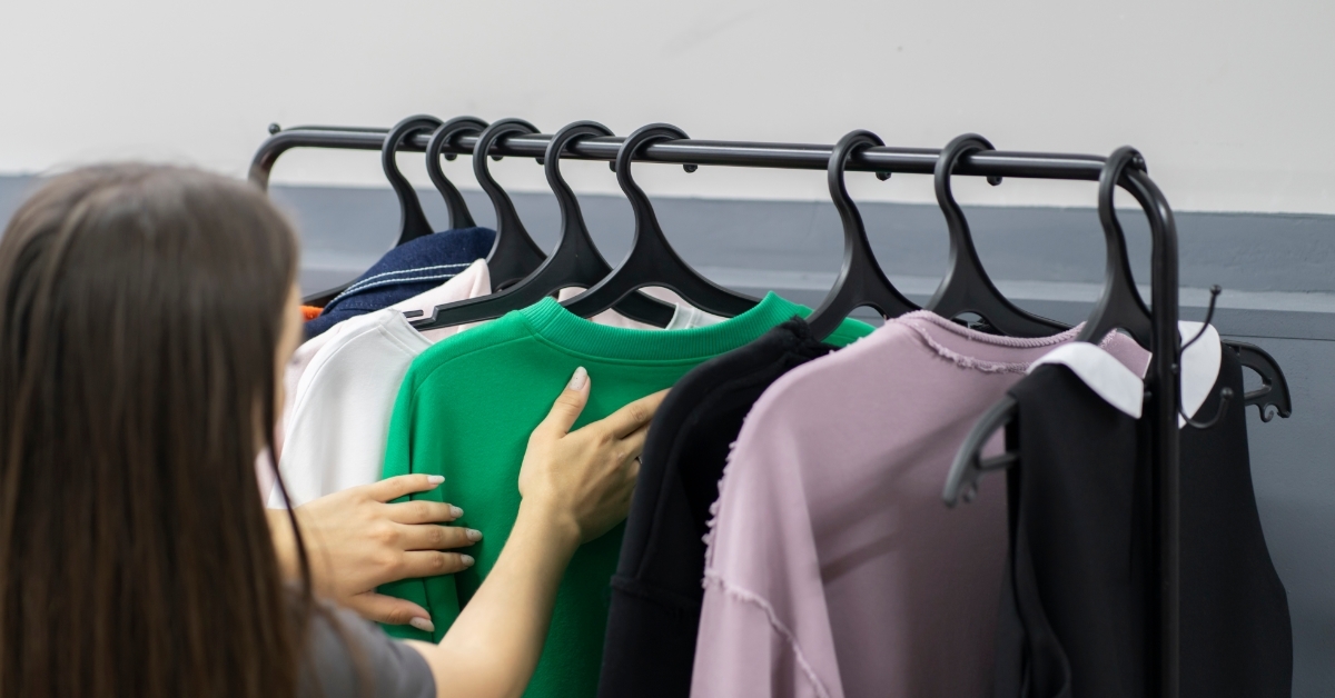 young woman choosing shirts on rack
