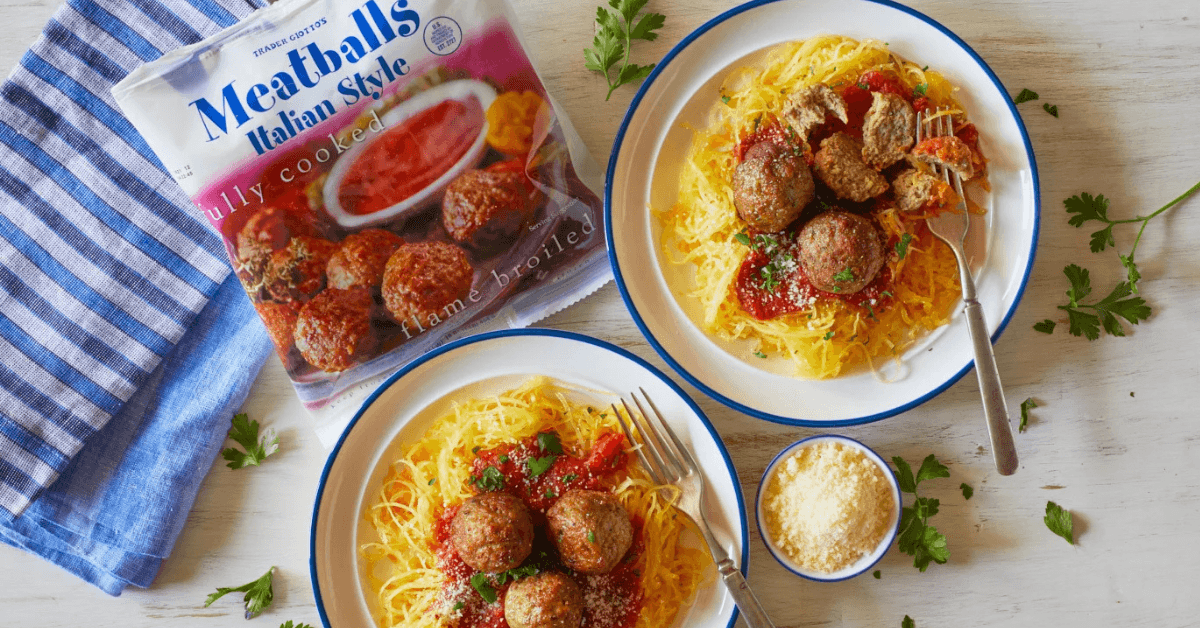 Two plates of spaghetti meatballs with bag of meatballs from Trader Joe's