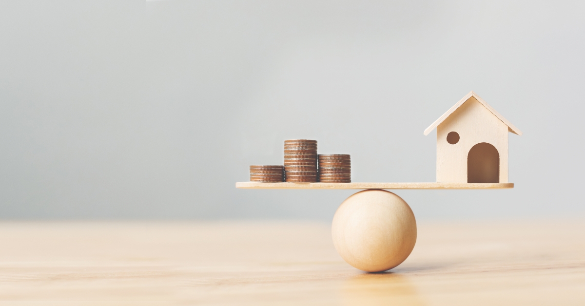 Wooden home and money coins stack on wood scale