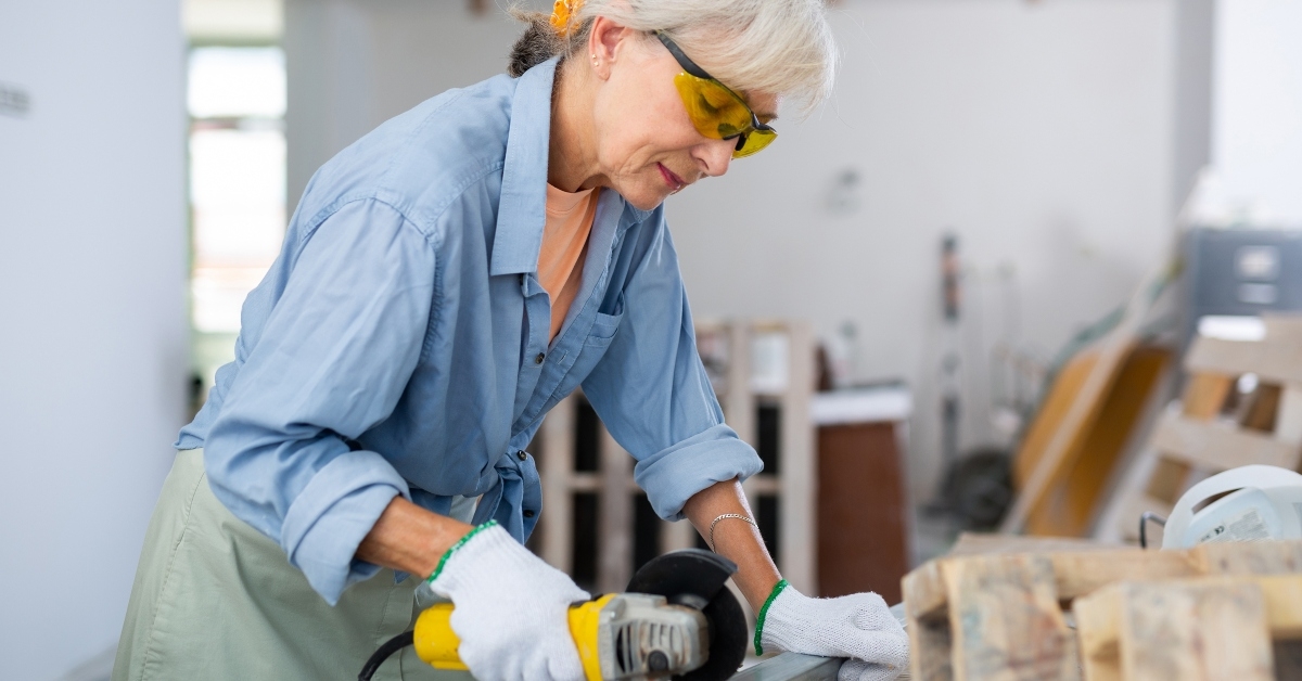 mature woman cutting metal profile using grinding machine