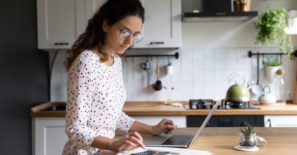 female standing in kitchen doing accounting work from home