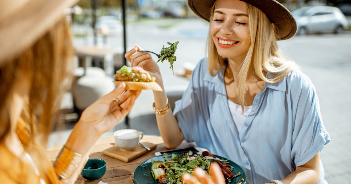 female best friends eating healthy food while sitting together