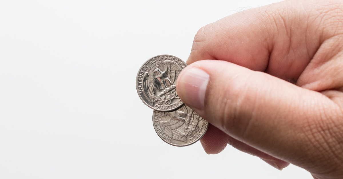 male hand holding two quarter dollar coins