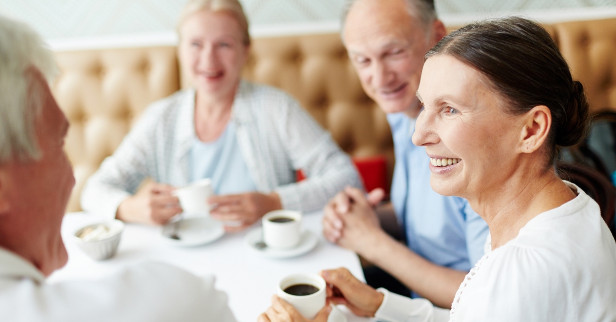 group of senior companions sitting at table in cafe