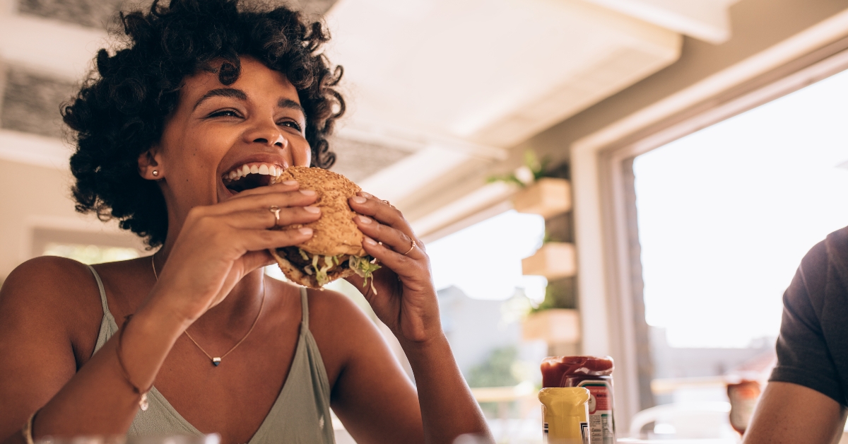 woman enjoying eating burger at restaurant 