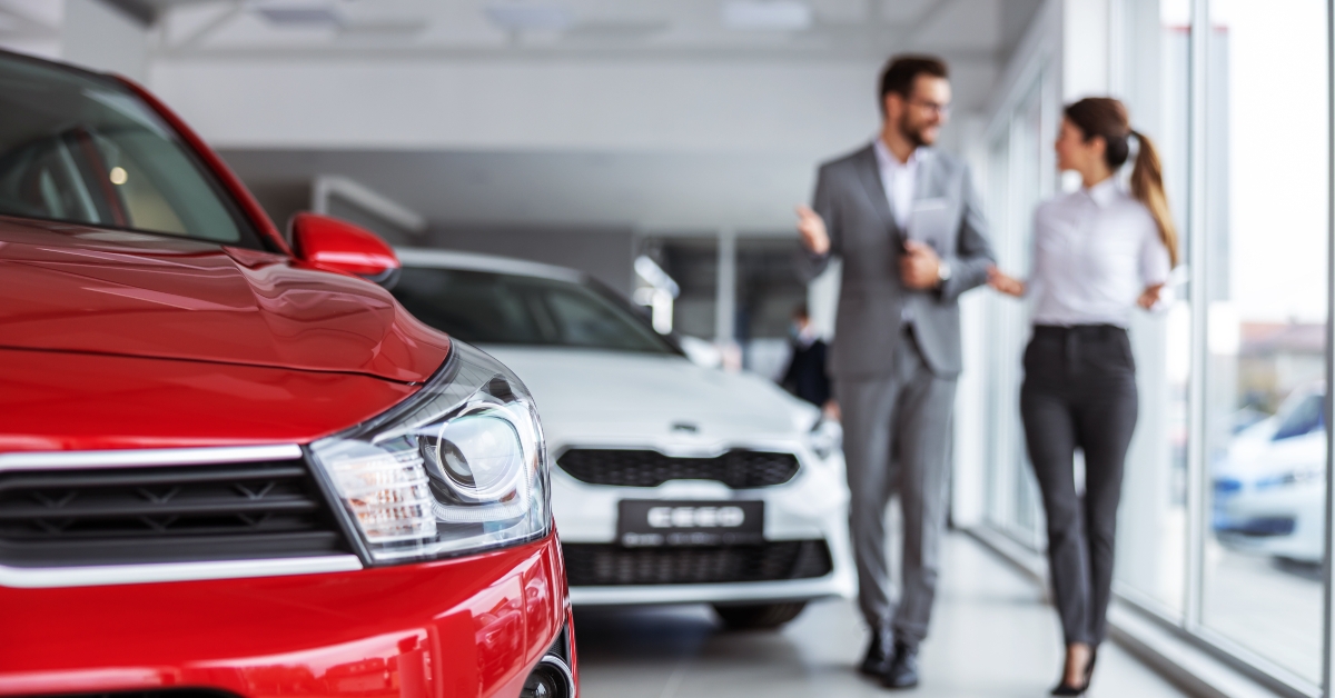 male car seller in suit walking around car salon with woman