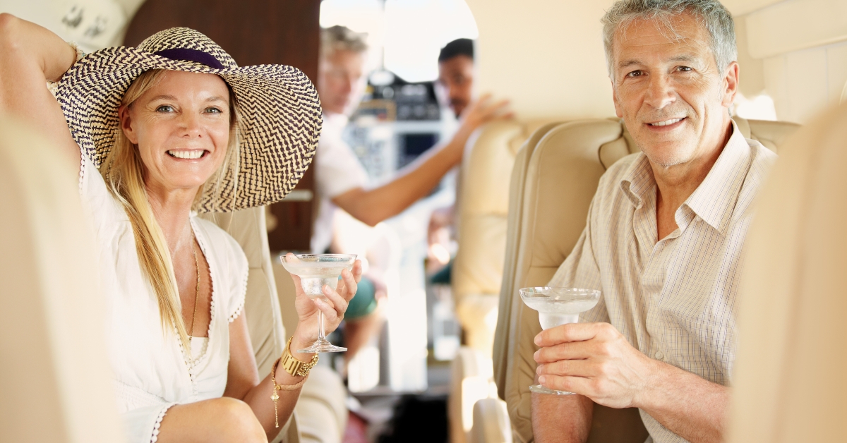 couple sitting in the back of a private jet while drinking cocktails