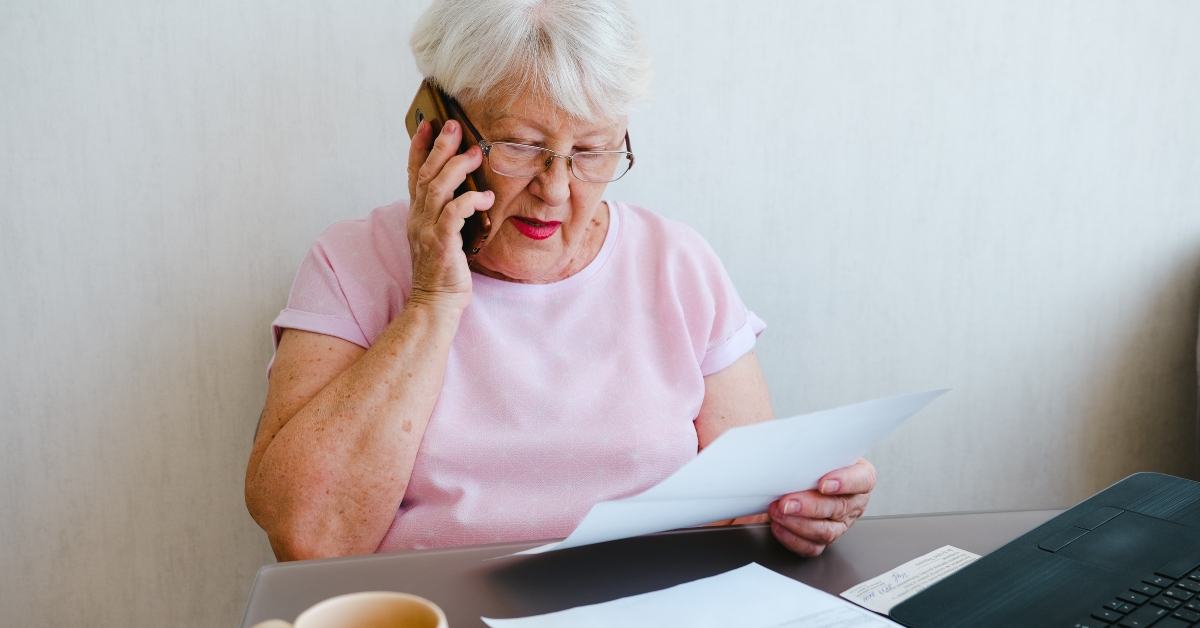 senior woman holding papers while talking on mobile phone