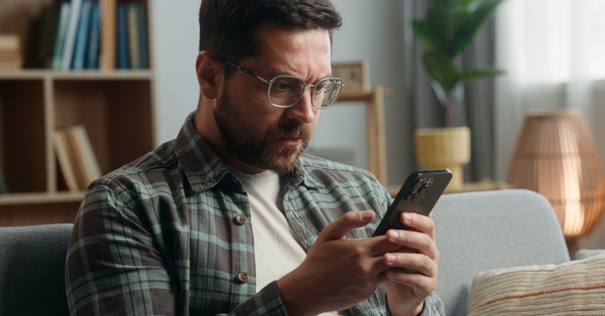 guy at home nervous looking at mobile phone