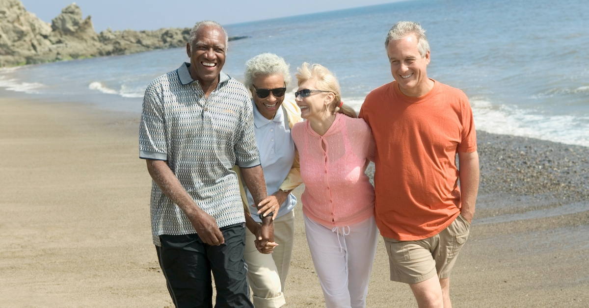 happy couples walking together on beach