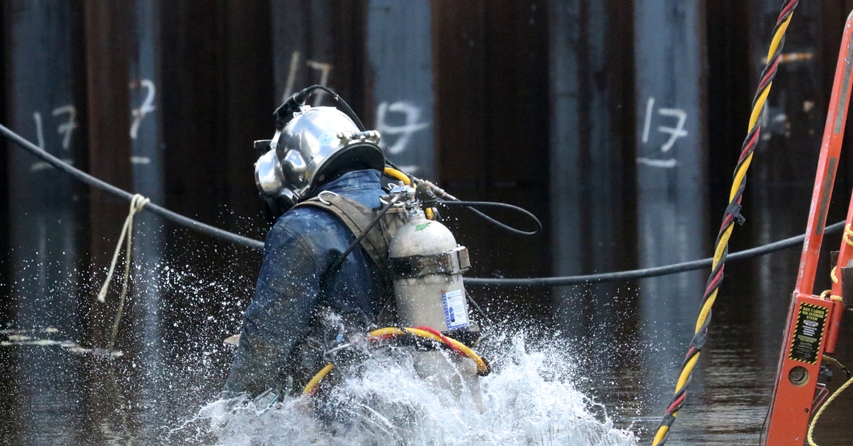 jumping in water to do underwater welding on construction project