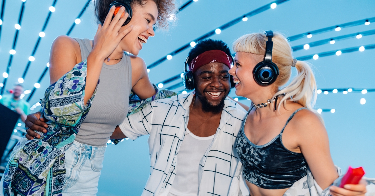 Friends wearing headphones and dancing together