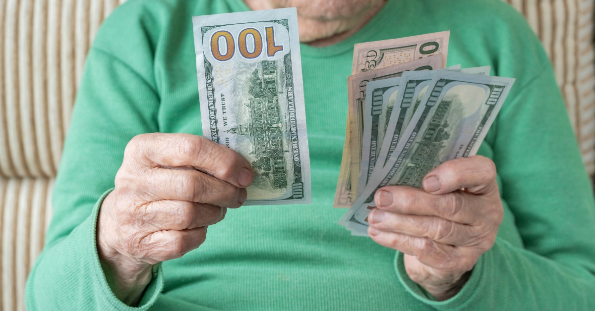 senior person holding american dollars