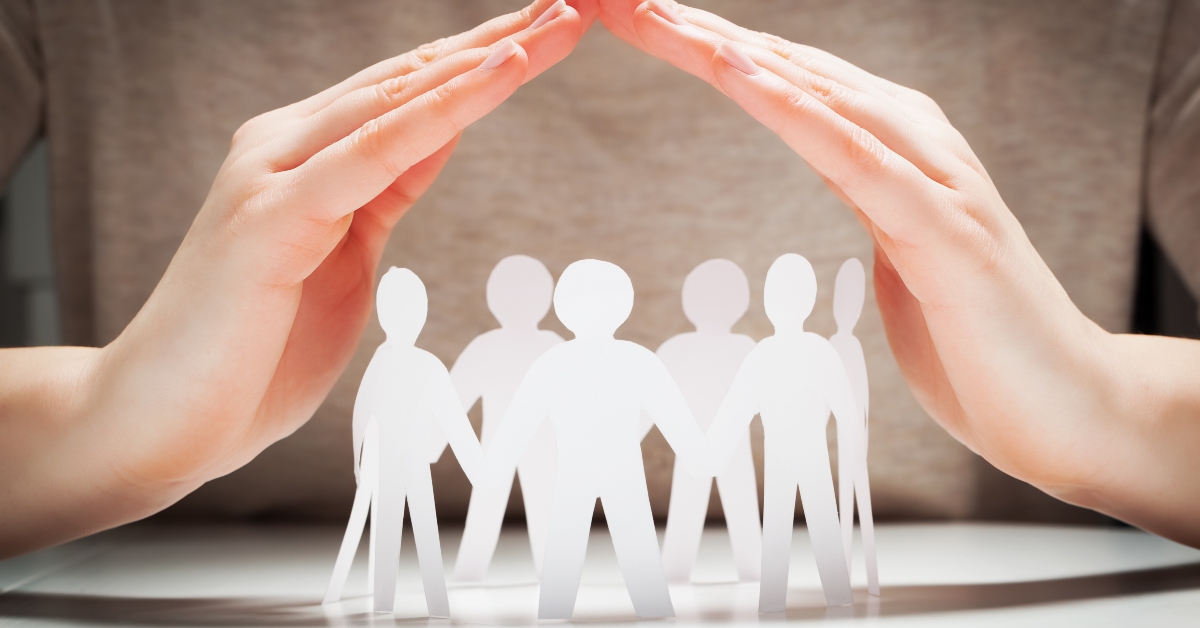 paper people under hands in gesture of protection