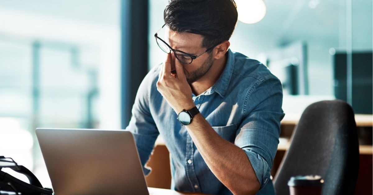 Stressed, tired and frustrated business man with headache at night from burnout or making mistake on laptop. 