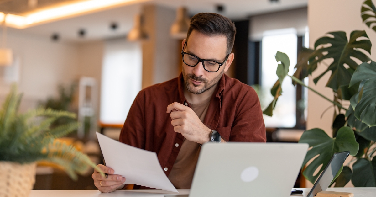 businessman reading documents while using laptop