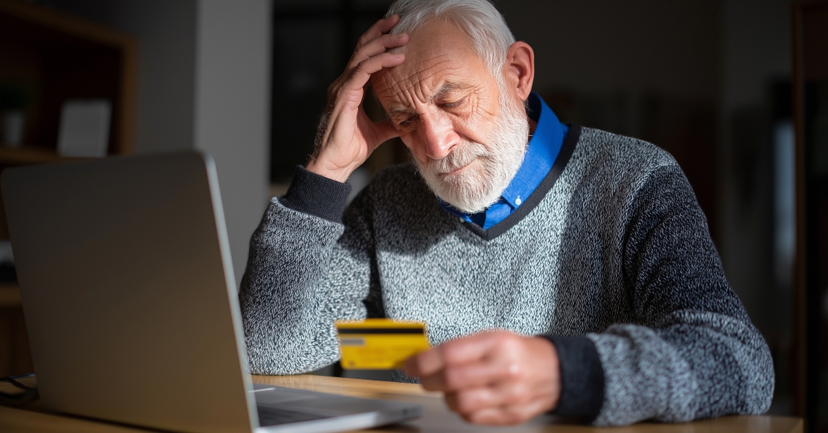 senior man looking worried while holding credit card