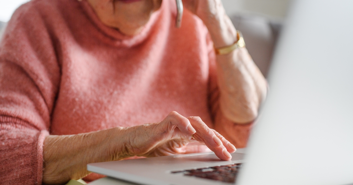 senior woman talking on phone while using laptop