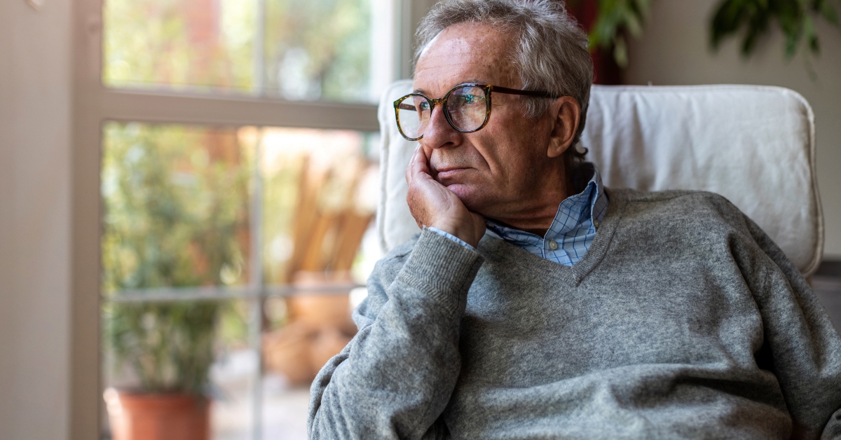 senior man looking out of window at home  