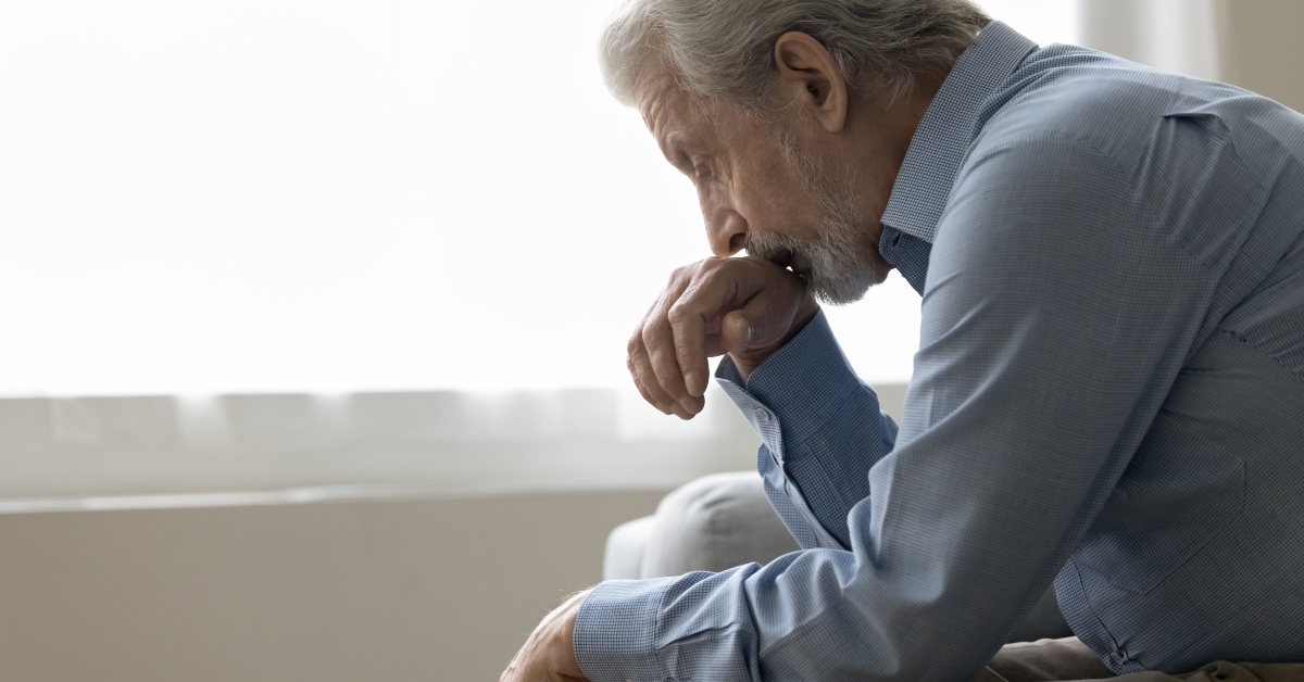 Depressed elder retired man sitting on home couch