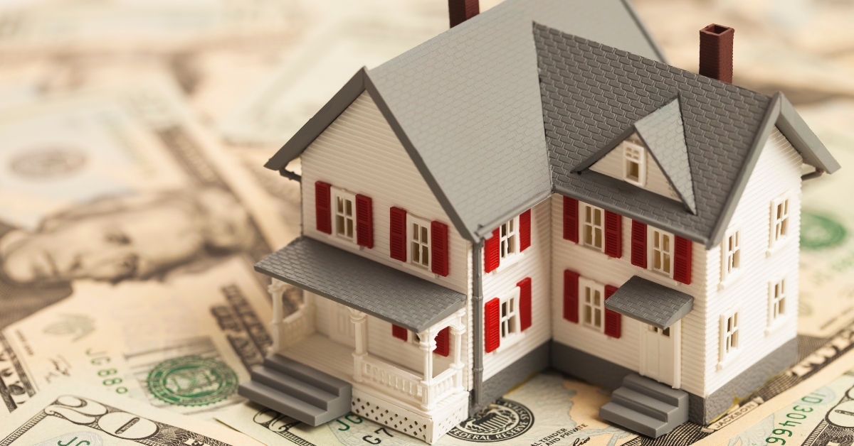 miniature house on pile of money 
