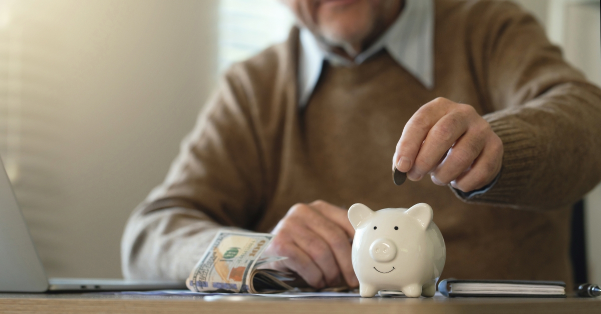 man hand putting money coins into a piggy bank