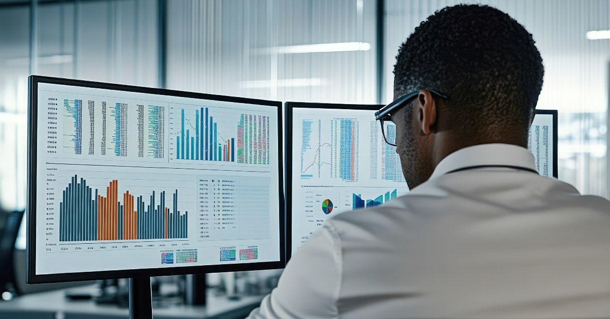 male analyst reviewing financial data on dual monitors