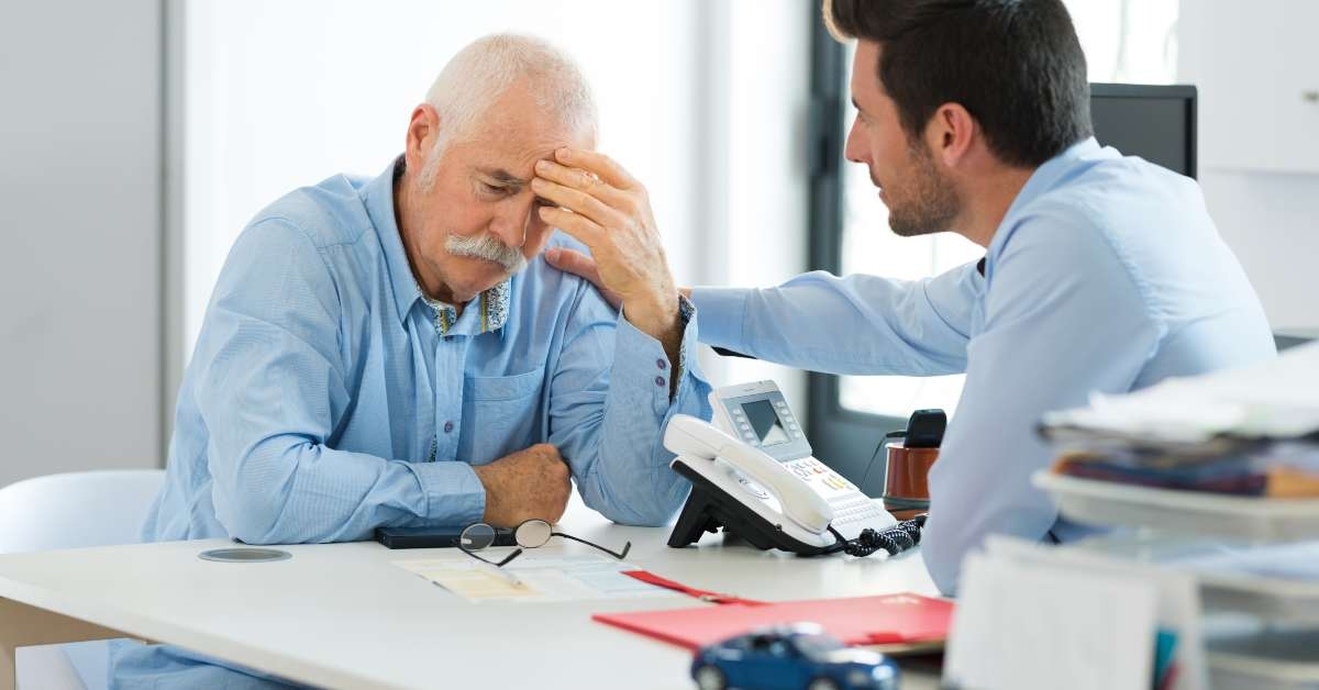 sad worker and younger one talking in office