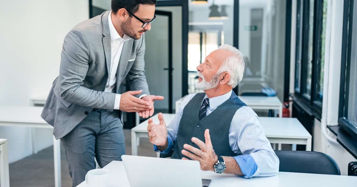 senior and young man discussing at work