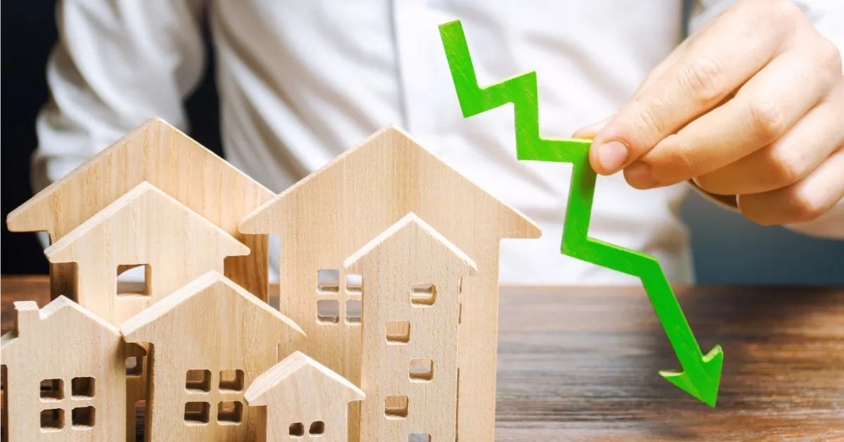 analyst holds down arrow near wooden houses