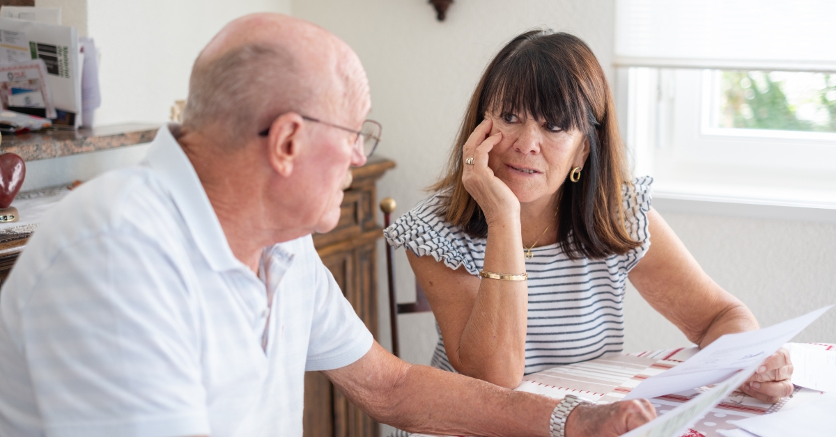 senior couple sitting at table with paper documents