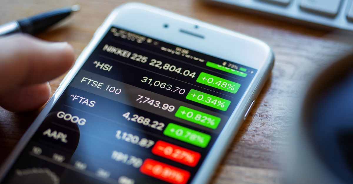 iPhone 6 on a desk displaying stock market information