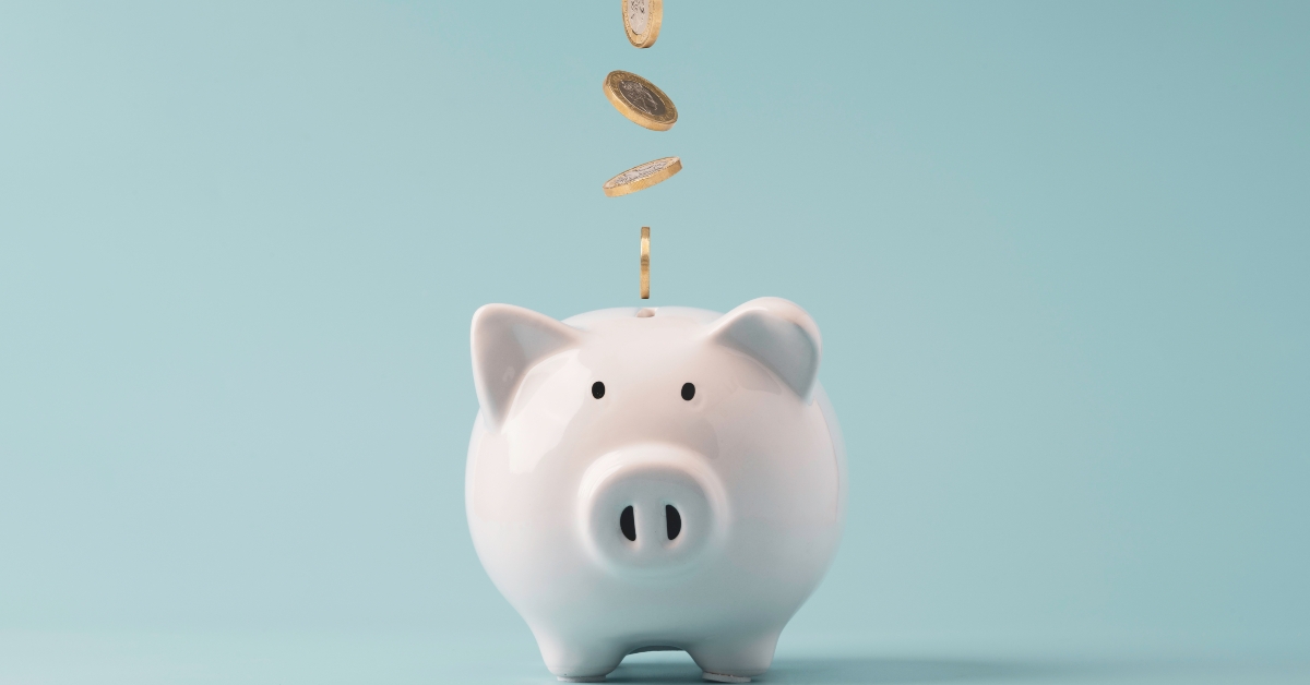 coins falling to white piggy bank