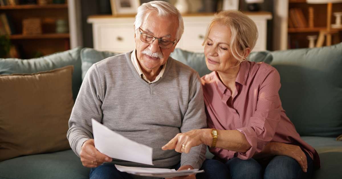 elderly couple sitting on a sofa reviews documents