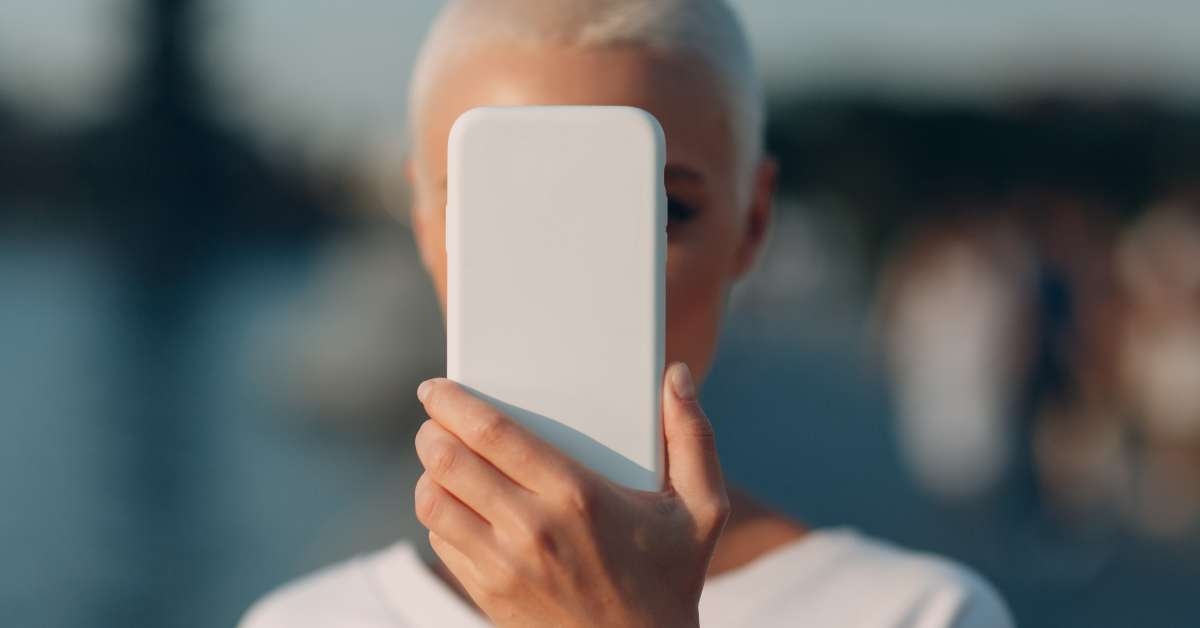 woman covering her face with smartphone