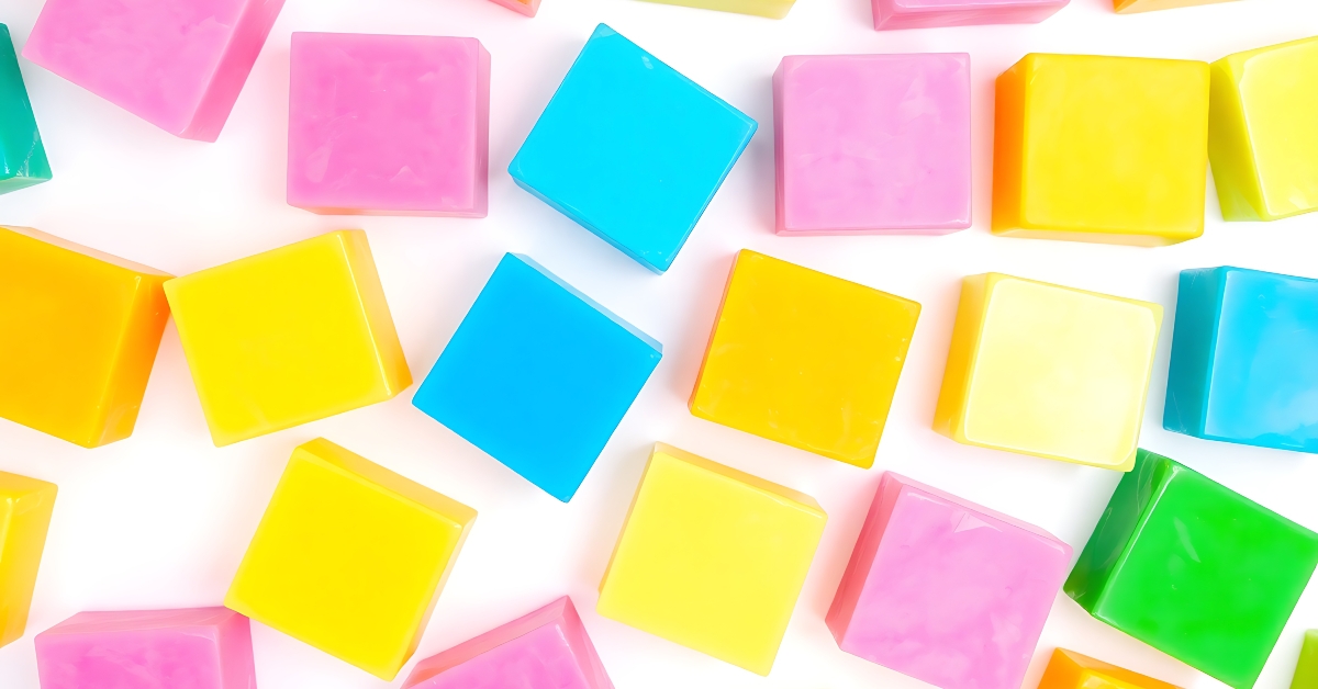 Scattered colorful square candies in shades of pink