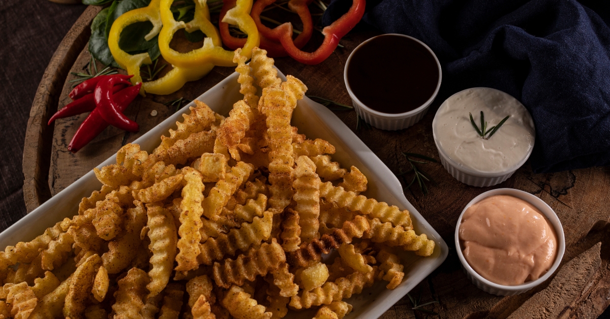 Fried crinkle-cut potatoes with sauces and Cajun seasoning