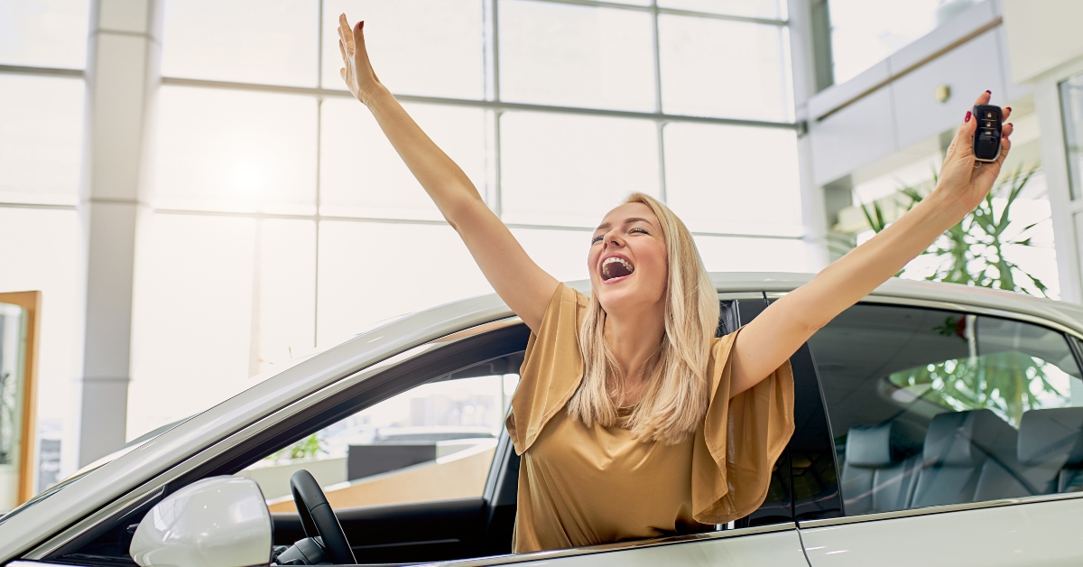 happy female holding keys inside a car