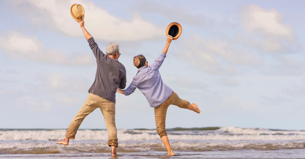 senior couple jumping on the beach
