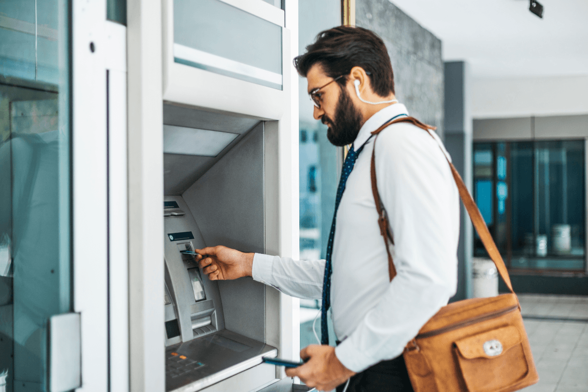 Man with work bag taking money out of atm