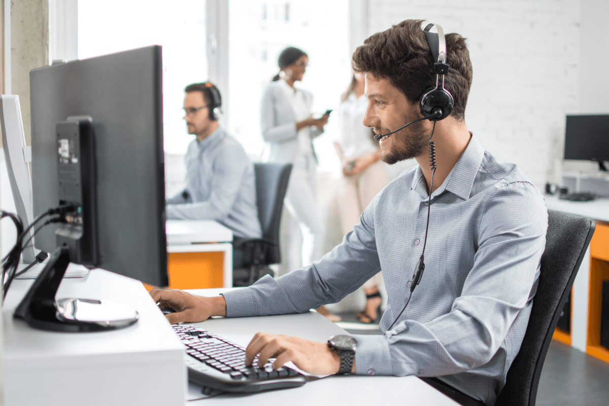 Banking customer service rep with headset sitting at computer, helping 82% of Gen Z who have contacted their bank’s customer service, many prefer speaking with a human over using automated support.