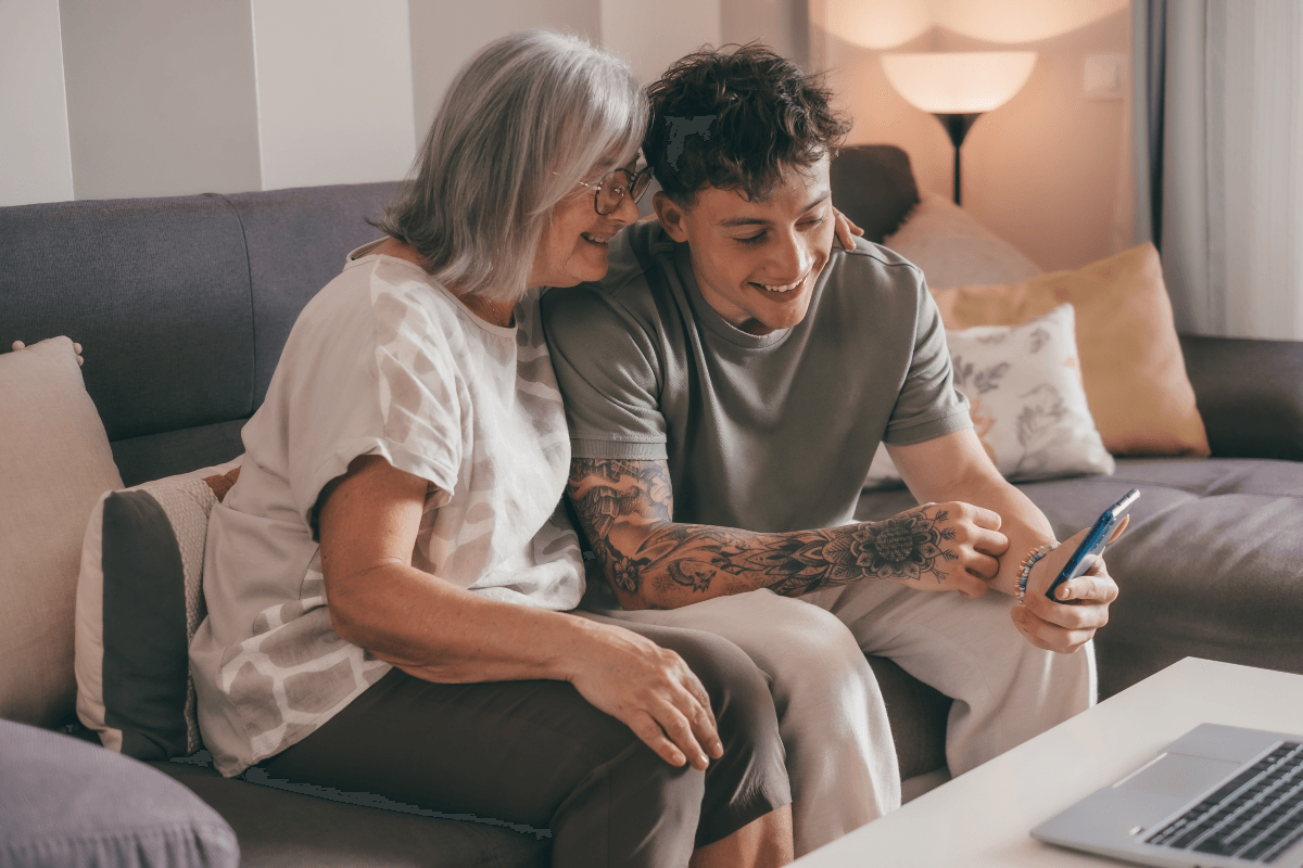 Older mother and Gen Z son looking at banking on laptop and cell phone, because 55% of Gen Z use the same bank as their parents, 48% have seriously considered switching their primary bank.
