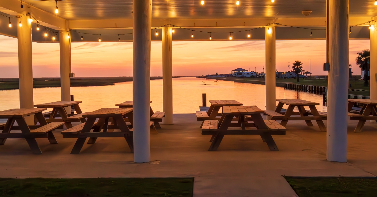 picnic tables are neatly arranged under a covered pavilion adorned