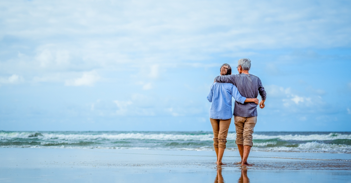 senior couple walking on the beach holding hands 