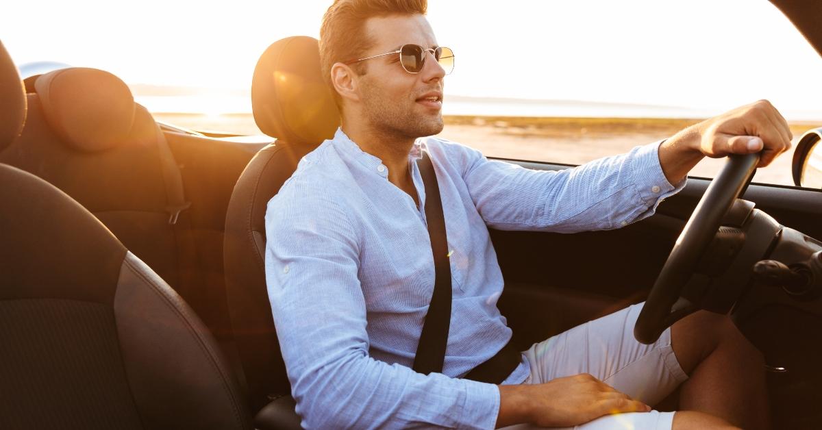 man driving convertible car by seaside at sunrise