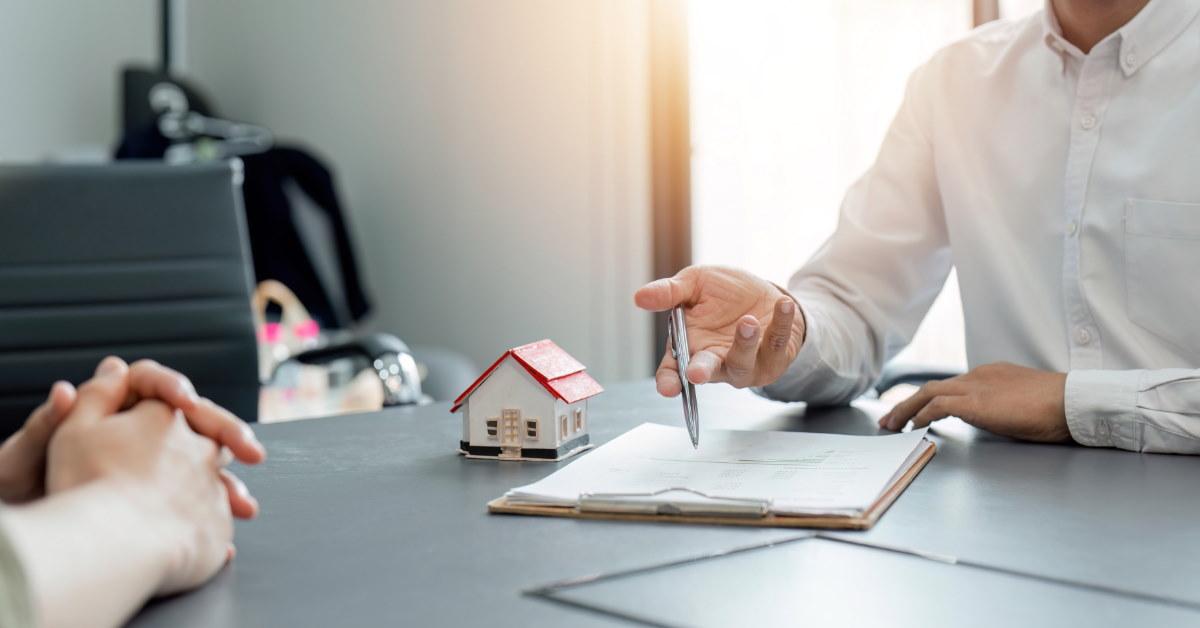 male real estate agent sitting in front of client explaining contract 