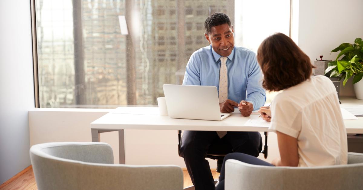 Female Client Signing Document In Meeting With Male Financial Advisor In Office