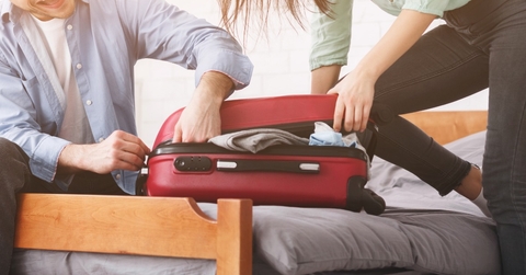 couple stuffing suitcase to avoid baggage fees