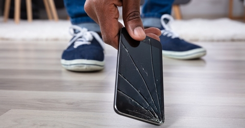 Person picking up phone with broken screen