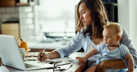 Working mother taking notes while calculating budget